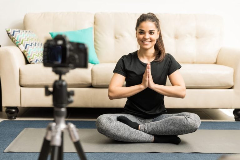 Gorgeous young Hispanic fitness blogger giving some advice on practicing yoga at home on video