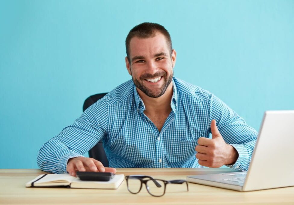 Smiling businessman calculates taxes and gesturing thumbs up