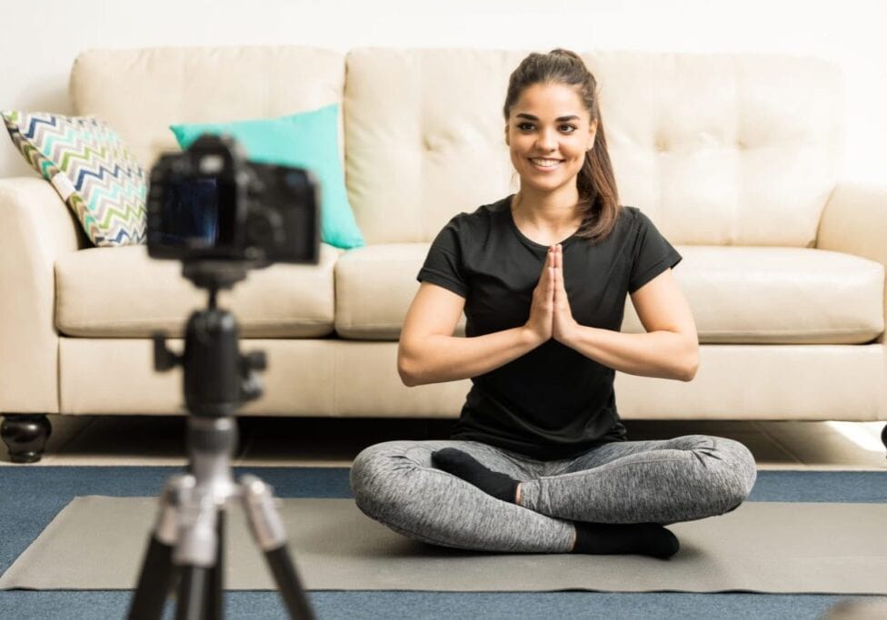 Gorgeous young Hispanic fitness blogger giving some advice on practicing yoga at home on video