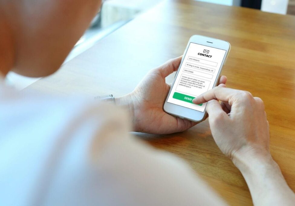 Man holding smartphone with use contact form on website